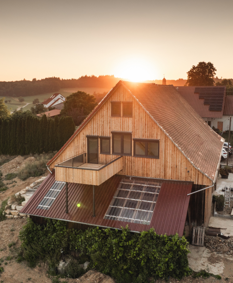 Residenz Nova: Haus mit Holzfassade und neuen Fenstern, Drohnenaufnahme bei Sonnenuntergang